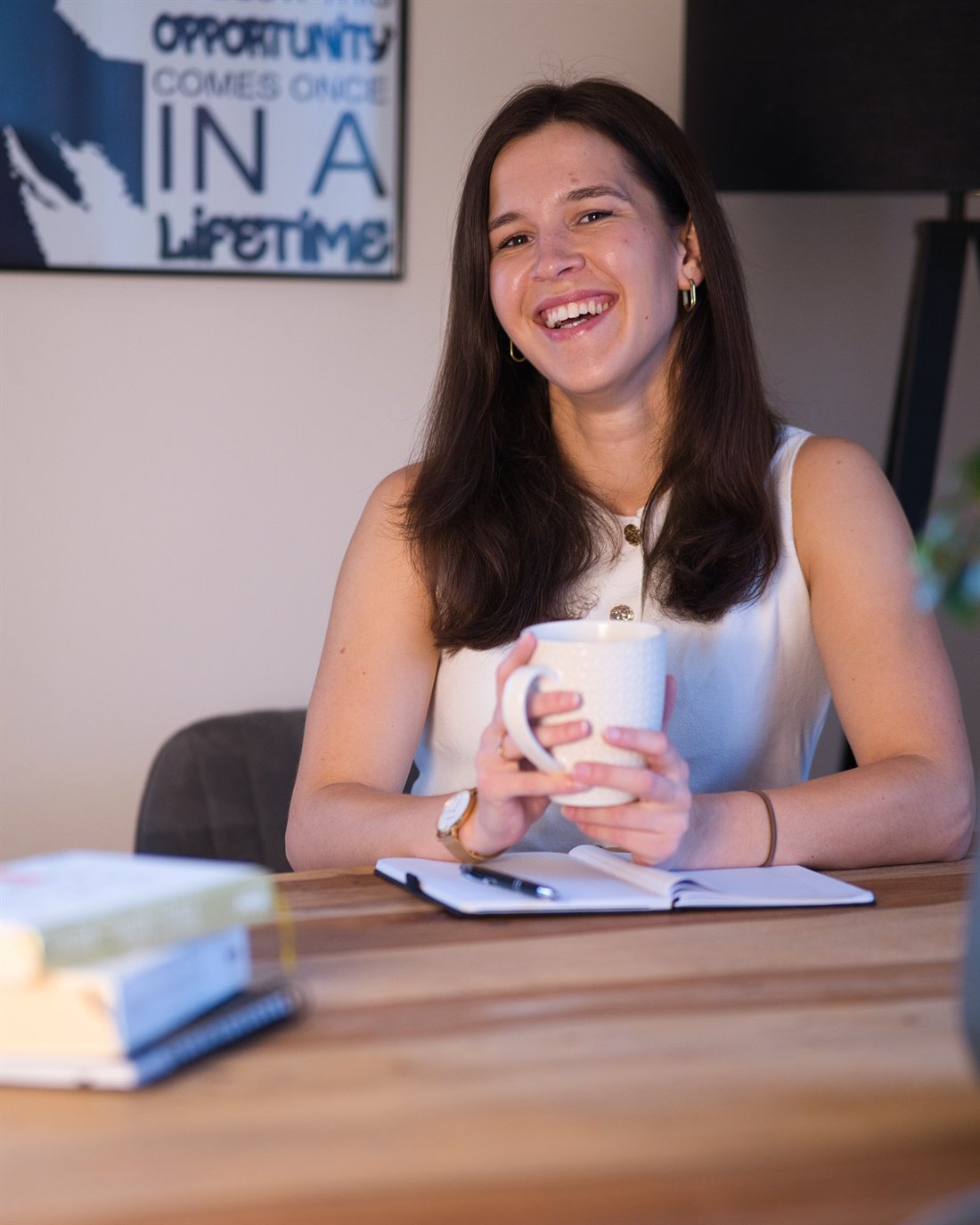 Leonie lacht herzlich am Tisch und hält eine Tasse in den Händen