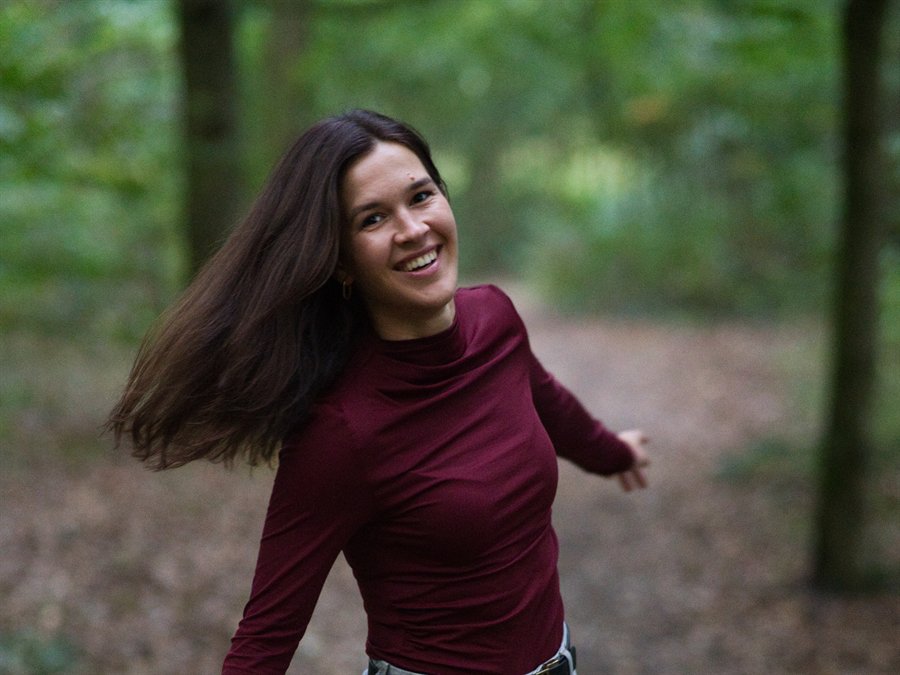 Leonie schwingt lachend ihre Haare im Wald, in Bewegung